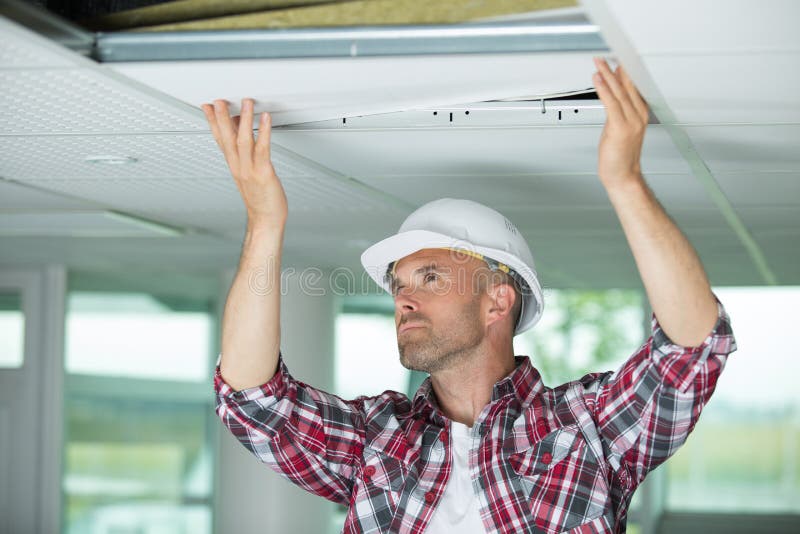 Man installing suspended ceiling in house. Man stock photography